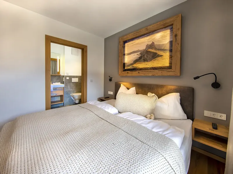 Schlafzimmer mit Doppelbett, daneben die offene Tür zum eigenen Bad