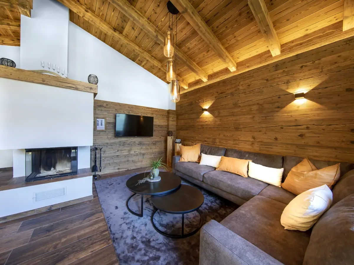 Der Kamin mit der Sitzecke davor an der Altholzwand