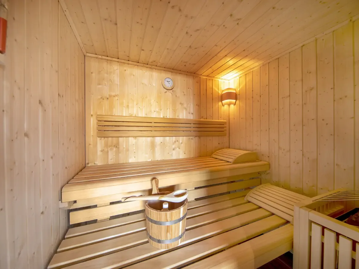 Die finnische Sauna aus hellem Holz mit Bank und Kübel