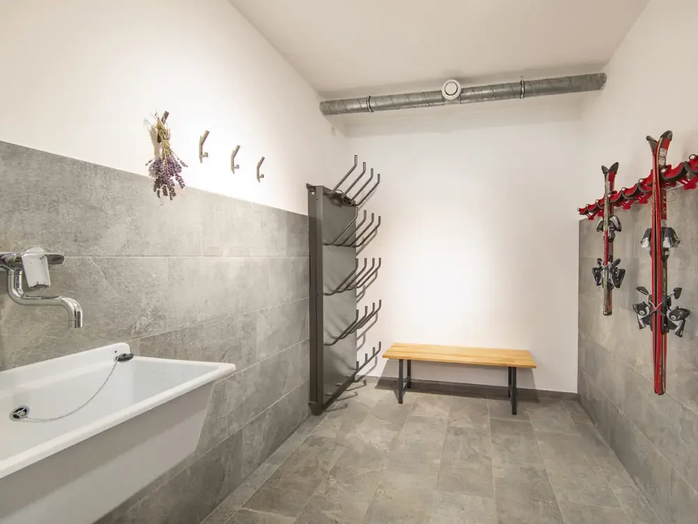 Der Skiraum mit Skihalterungen an der Wand, Bank und Becken
