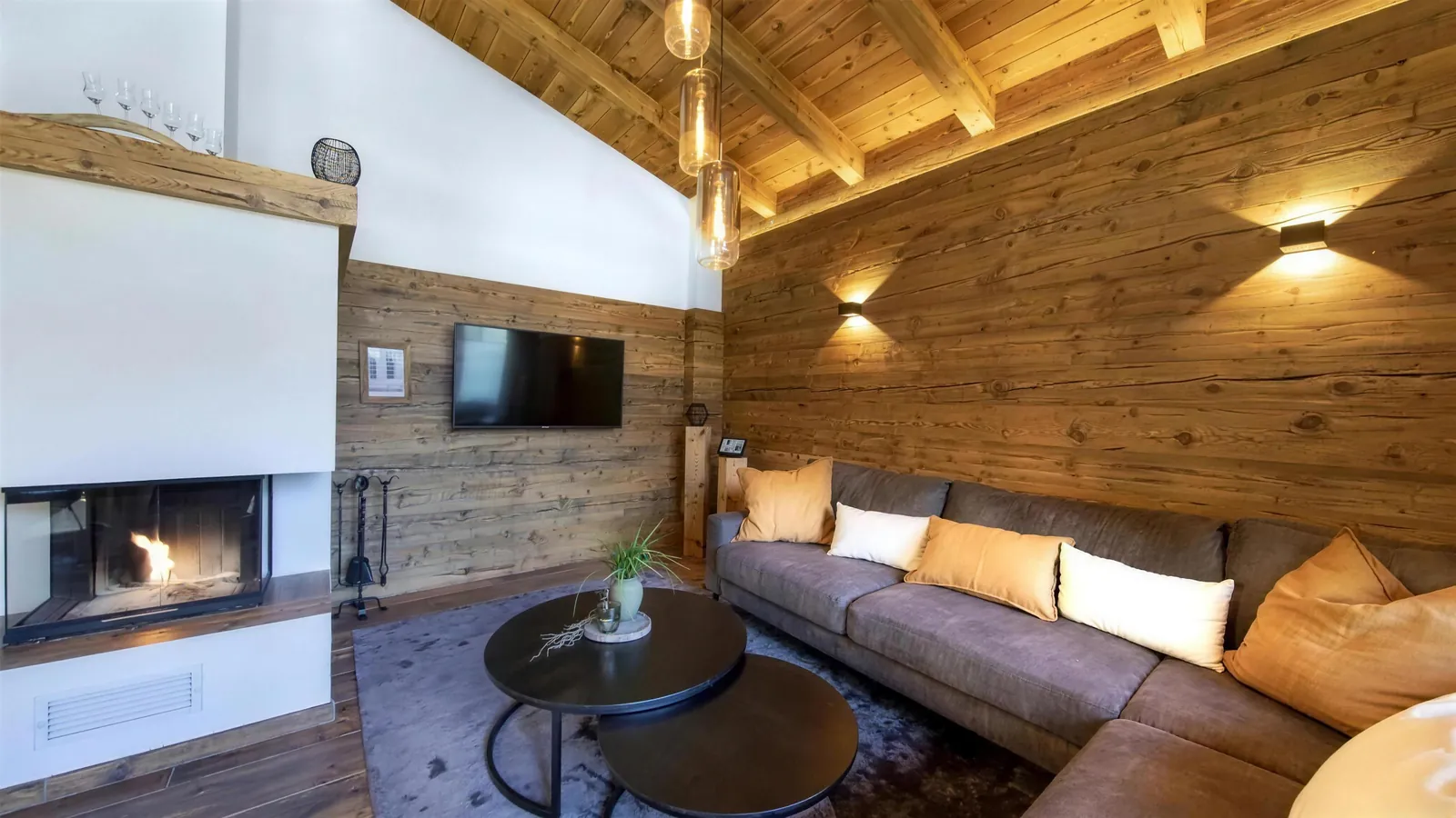 Drinnen: der Kamin brennt, davor die Sitzecke an der Altholzwand