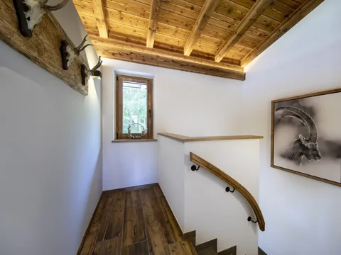 Die Holztreppe zwischen den Etagen, mit Handlauf an der weißen Wand