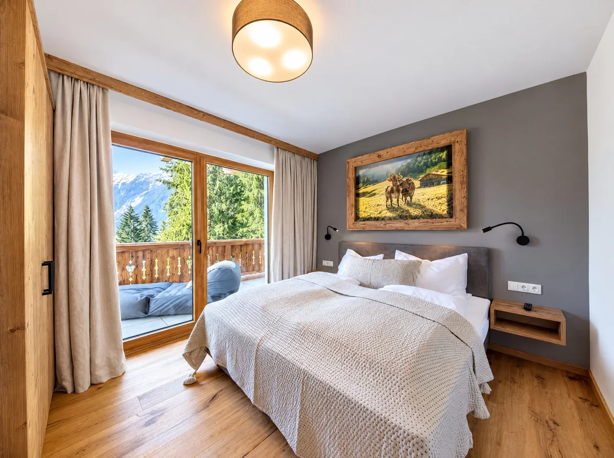 Schlafzimmer mit Doppelbett, Fenstertür zum Balkon und Blick auf die Berge